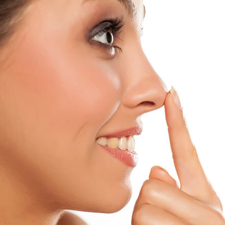 mulher com rosto de perfil tocando a ponta do nariz com o dedo