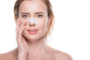 mulher com curativo de Rinoplastia no nariz - vou sentir dor apos a rinoplastia
