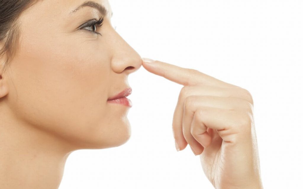 Mulher com dedo no nariz mostrando resultado de rinoplastia