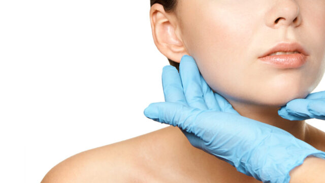 rosto feminino sendo tocado pelas mãos do médico com luvas azuis mostrando mentoplastia