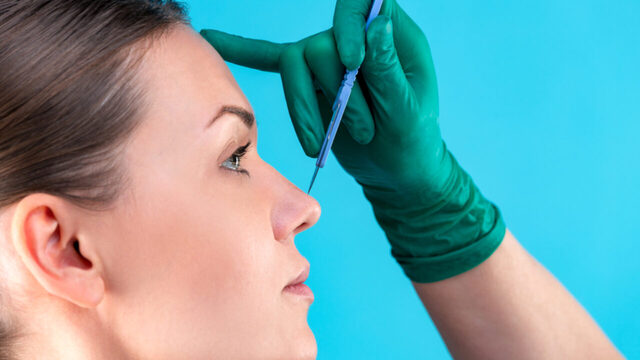mão de médico avaliando nariz de mulher para rinoplastia
