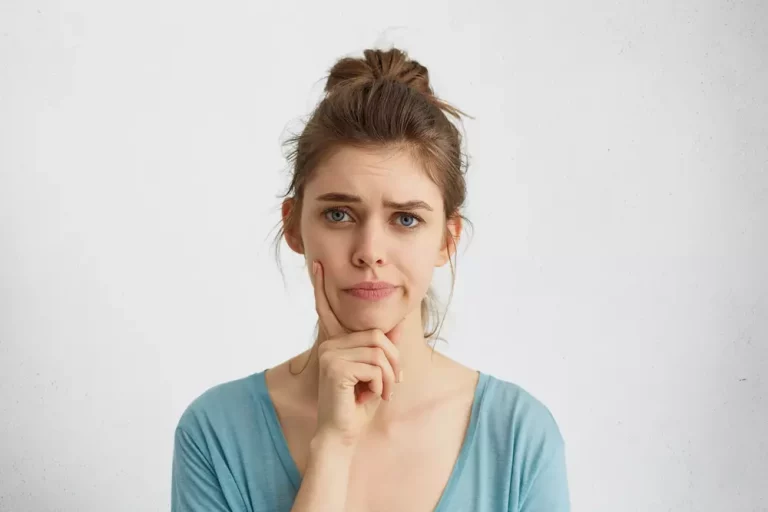 rosto de mulher mão no queixo pensando - qual a anestesia adequada para a rinoplastia?