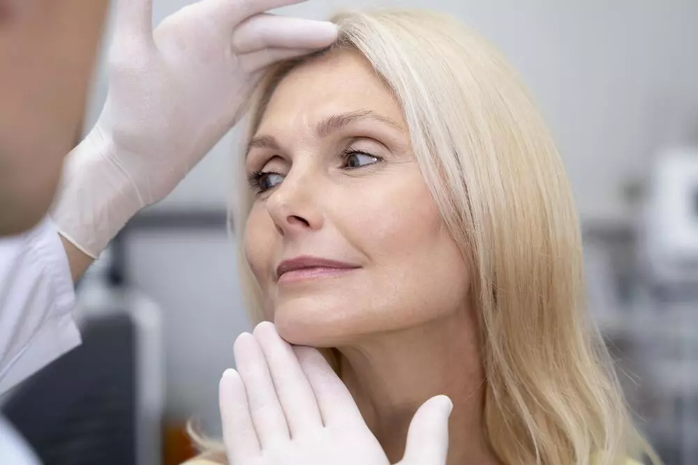 medico-examinando-rosto-de-mulher-madura-bonita-para-rinoplastia-e-lifting-facial