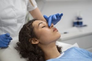 O que Fazer no Pós-Operatório Imediato de Rinoplastia: Guia Completo - mãos de médico com luvas tocando nariz de paciente de rinoplastia